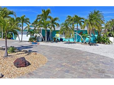 Tropical home with circular driveway, palm trees, and unique facade at 10404 Sandpiper W Rd, Bradenton, FL 34209