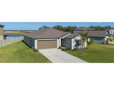 One-story home with brown garage door, landscaping, and a view of a lake at 13608 Sunset Sapphire Ct, Parrish, FL 34219