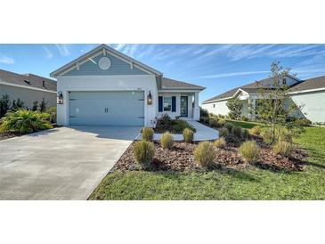 Curb appeal abounds in this charming one-story home, featuring a light blue garage door and well-manicured landscaping at 14155 Campfire Ct, Parrish, FL 34219