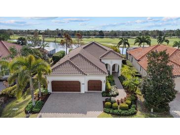 Luxury home with tile roof, two-car garage, and landscaped yard; golf course view at 15608 Leven Links Pl, Lakewood Ranch, FL 34202