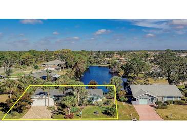 Beautiful waterfront home with lush landscaping, mature palm trees, and brick driveway on a sunny day at 309 South Dr, Nokomis, FL 34275