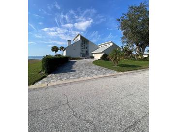 Contemporary waterfront home with a patterned driveway, lush landscaping, and attached garage at 3104 Bay Dr, Bradenton, FL 34207