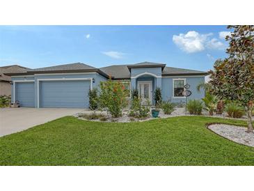 Beautiful light blue house with a 3-car garage and nicely landscaped front yard at 12607 Wheatgrass Ct, Parrish, FL 34219