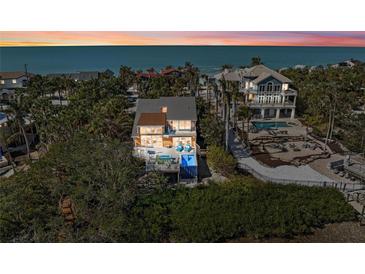 Beautiful beach house featuring palm trees and ocean views at sunset at 140 N Casey Key Rd, Osprey, FL 34229
