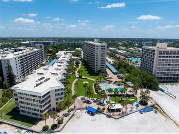 Aerial view of a beachfront community with multiple buildings, lush landscaping, and a pool at 5916 Midnight Pass Rd # 103, Sarasota, FL 34242