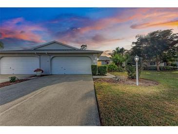 Two-car garage, landscaped lawn, and walkway leading to entrance at sunset at 6009 Bonaventure Pl, Sarasota, FL 34243