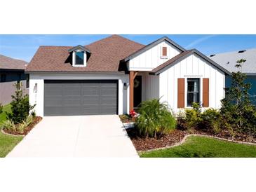 White farmhouse exterior with brown roof, landscaping, and a two-car garage at 8219 Abalone Loop, Parrish, FL 34219