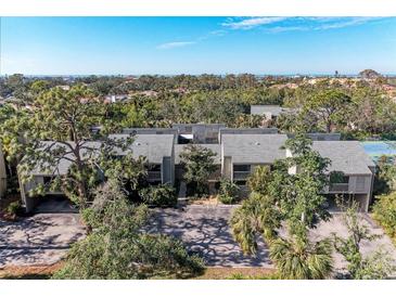 Aerial view of condo community with ocean views, lush landscaping, and tennis courts at 362 Pine Run Dr, Osprey, FL 34229