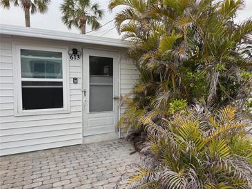 Charming cottage-style home featuring a white exterior, palm tree, and quaint brick walkway at 2601 Gulf N Dr # 613, Bradenton Beach, FL 34217