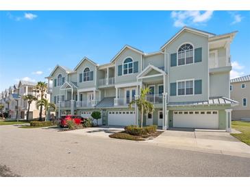 Three-story building with light green exterior, multiple garages, and landscaping at 10390 Longshore Rd # 83, Placida, FL 33946