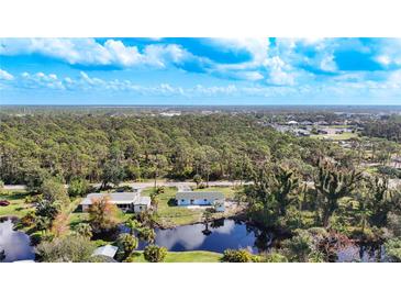 An aerial view of the house with a pond and many trees surrounding the home at 712 N Elm St, Englewood, FL 34223