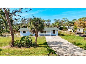 Charming single-story home with a gravel driveway, lush lawn, and a welcoming porch at 712 N Elm St, Englewood, FL 34223