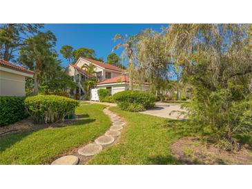 Exterior of two-story condo with landscaped grounds and walkway at 7610 Fairway Woods Dr # 205, Sarasota, FL 34238