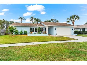 Light blue house with a white garage door, landscaping, and a spacious lawn at 1670 Oak View Dr, Sarasota, FL 34232