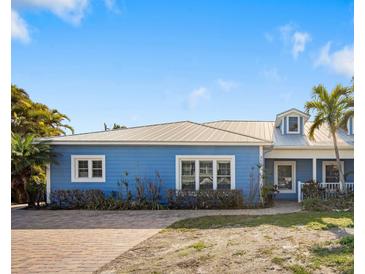 Charming blue house with metal roof, paved driveway, and nicely landscaped at 215 75Th St, Holmes Beach, FL 34217