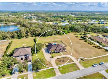 Expansive aerial view of a single-Gathering home, showcasing a circular driveway, swimming pool and sizable backyard at 3310 Twin Rivers Trl, Parrish, FL 34219