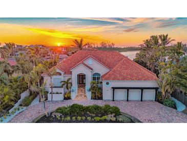 Stunning waterfront home with lush landscaping, a three-car garage, and a beautiful tile roof at sunset at 400 N Washington Dr, Sarasota, FL 34236