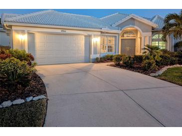 Night view of single-story home with gray exterior, two-car garage, and landscaping at 4066 Via Mirada, Sarasota, FL 34238