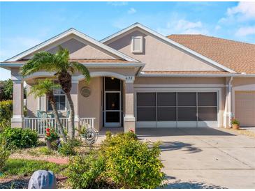 Tan house with a two-car garage and nicely landscaped yard at 4153 Lenox Blvd, Venice, FL 34293