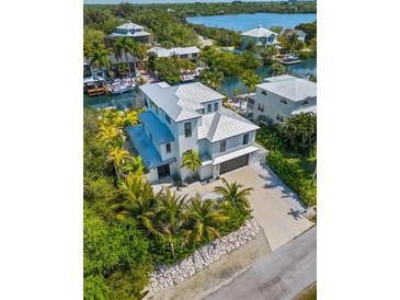 Aerial view of a waterfront home with a two-car garage and lush landscaping at 130 Burns Rd, Terra Ceia, FL 34250