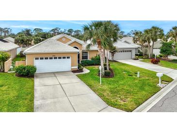 Tan house with white garage door, palm trees, and well-manicured lawn at 1364 Berkshire Ct, Venice, FL 34292