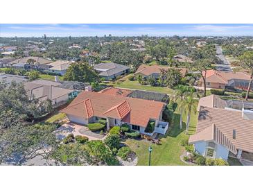 An aerial view of a home with a red tile roof, a screened-in pool, and lush landscaping at 1426 Landview Ln, Osprey, FL 34229