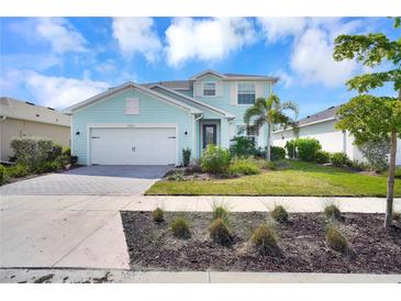 Charming two-story home with a light blue exterior, two-car garage, and beautifully landscaped front yard at 17395 Palmetto Pass Ln, Punta Gorda, FL 33982