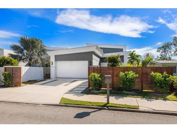 Modern home with attached two-car garage, landscaped yard, and wooden privacy fence at 2254 Hawthorne St, Sarasota, FL 34239