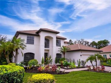 Two-story house with a white exterior, brown roof, and landscaped yard at 7724 Us Open Loop, Lakewood Ranch, FL 34202