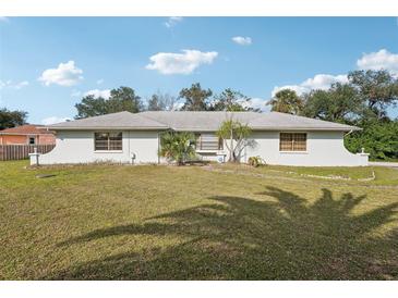 Charming single-story home with a well-maintained lawn and mature trees offering shade and curb appeal at 20313 Navajo Ln, Port Charlotte, FL 33952