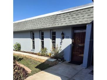 Exterior view of a condo with a gray roof, light gray walls, and landscaping at 4160 Fruitville Rd # 32, Sarasota, FL 34232