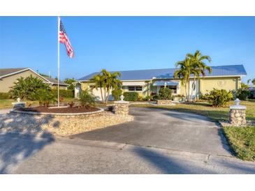 Charming home with a well-manicured front yard, palm trees, and a welcoming driveway with an American flag at 4607 Mangrove Point Rd, Bradenton, FL 34210