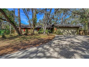 Ranch style home with green exterior, red shutters, and a large driveway at 5180 Meldon Cir, Sarasota, FL 34232