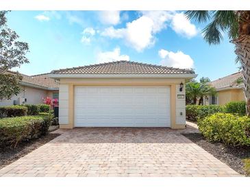 Two-car garage with a brick paver driveway and well-maintained landscaping at 6063 Benevento Dr, Sarasota, FL 34238