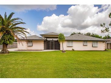 Single-story home with a large lawn, palm trees, and a covered patio at 613 Chevy Chase Dr, Sarasota, FL 34243