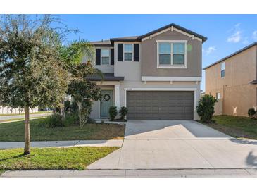 Two-story home showcasing a manicured lawn, tidy landscaping, and a welcoming entrance with attached two-car garage at 6218 Apple Snail Ave, New Port Richey, FL 34653