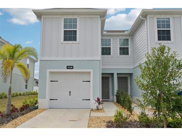 Charming townhouse with a white garage door, light blue trim, and well-maintained landscaping at 14180 Crimson Ave, Bradenton, FL 34211