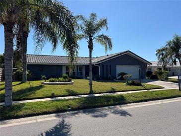 Landscaped front yard with lush green grass and mature palm trees creates great curb appeal at 2930 Tuckerstown Dr, Sarasota, FL 34231