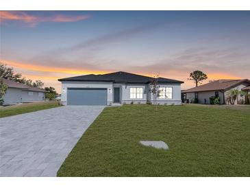 New home exterior at dusk, featuring light-colored siding and gray paver driveway at 514 Santiguay St, Punta Gorda, FL 33983