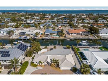 Wide aerial view of canal-front homes and Gulf, featuring docks, boats, pools, and landscaping at 627 Dundee Ln, Holmes Beach, FL 34217