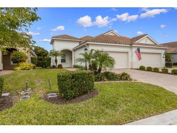 Charming home boasts a beautifully landscaped front yard, an arched entryway, and a two-car garage at 6912 Playa Bella Dr, Bradenton, FL 34209