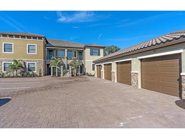 Attractive condo building exterior with garages, lovely landscaping, and stone accents at 12410 Osorio Ct # 201, Sarasota, FL 34238