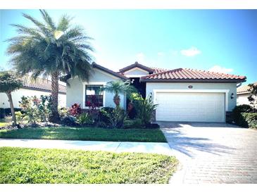 Charming single-story home with a well-manicured lawn, tropical landscaping, and a two-car garage at 12675 Richezza Dr, Venice, FL 34293