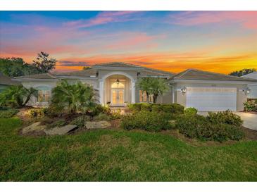 Charming home with a well-manicured lawn, lush tropical landscaping, and a colorful sunset sky at 2023 Micanopy Trl, Nokomis, FL 34275