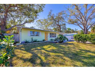 Light green house with a yellow door, surrounded by lush landscaping at 2040 Palm Ter, Sarasota, FL 34231