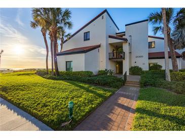 Beautiful condo building with a manicured lawn, walkway and tropical landscaping at 2089 Gulf Of Mexico Dr # G1-205, Longboat Key, FL 34228