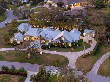 Stunning aerial view of a luxury estate featuring a circular driveway, manicured landscaping, and a metal roof at 3759 Beneva Oaks Blvd, Sarasota, FL 34238