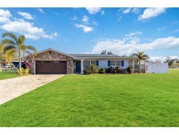 Charming single-story home featuring a stone facade, well-manicured lawn, and a paved driveway at 6001 Firefly Ln, Apollo Beach, FL 33572