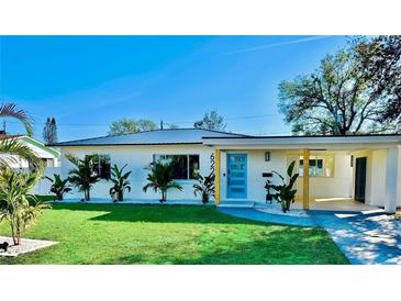 Charming single-story home with a well-manicured lawn, bright blue door, and modern architectural details at 6226 21St N Ave, St Petersburg, FL 33710