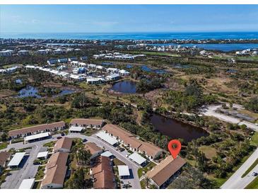 Gorgeous aerial view of the community, showcasing a tranquil pond and the beautiful coastline at 6796 Gasparilla Pines Blvd # 45, Englewood, FL 34224